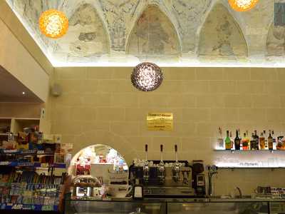 Entrando ci troviamo di fronte al bancone, costituito da una lastra chiarissima di marmo. Dietro di esso scorgiamo una nicchia luminosa racchiusa da un arco che prima ospitava l�acquasantiera e oggi invece ospita un espositore di t� e tisane